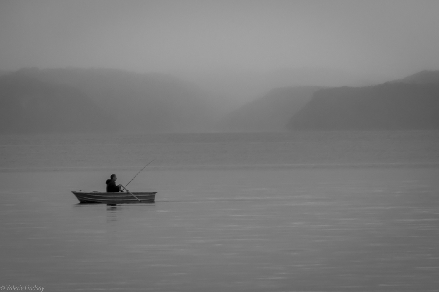 Man fishing on misty morning